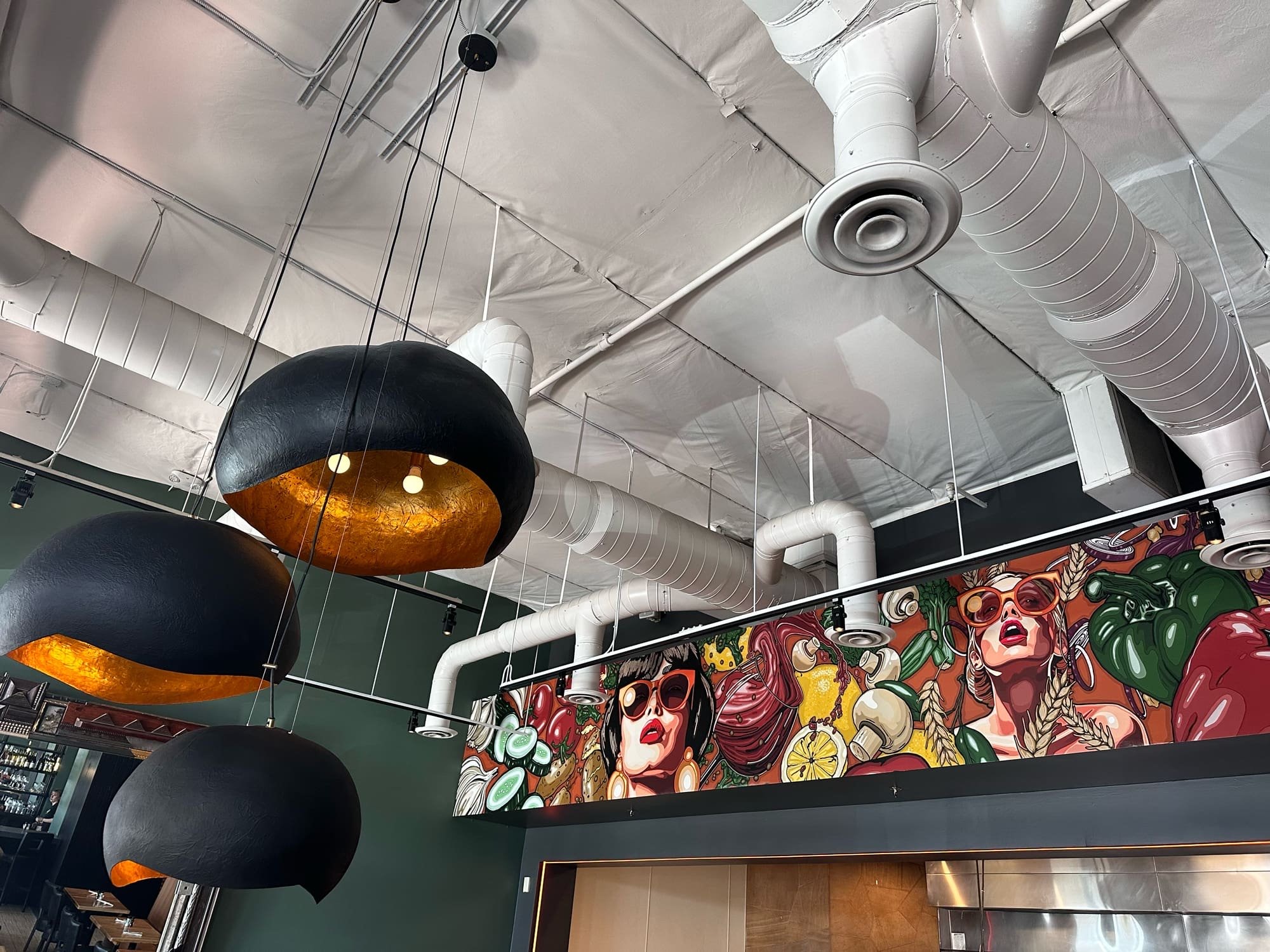 Bar with black dome pendants and a painted mural at Pita Jungle Arcadia